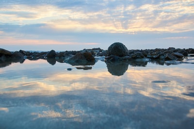 The formation of clouds during the day in the water under the black rock
